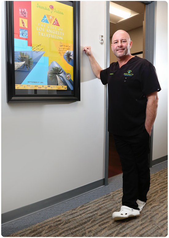 Gem Health and Wellness - Dr Kuzdak Standing with Triathlon Poster